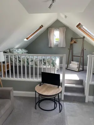 a attic room with a crib and a chair at Sea Glimpses Studio Port Isaac in Port Isaac