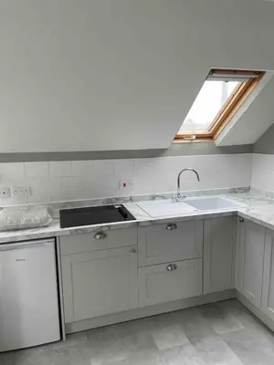 a kitchen with white cabinets and a sink and a window at Sea Glimpses Studio Port Isaac in Port Isaac