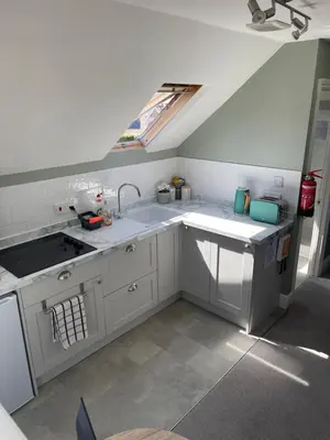 a kitchen with white cabinets and a sink and a window at Sea Glimpses Studio Port Isaac in Port Isaac