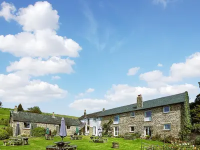 a stone house with tables and umbrellas in front of it at Culver Cottage - Uk48987 in Looe