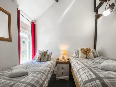 two twin beds in a room with a window at Linney Cottage - Uk48986 in Looe