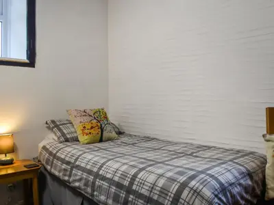 a small bedroom with a bed with a plaid blanket at Linney Cottage - Uk48986 in Looe