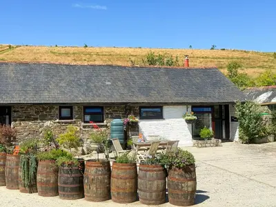 a building with a bunch of barrels with plants at Linney Cottage - Uk48986 in Looe