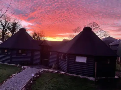 a log cabin with a sunset in the background at The Wizards Cauldron -Harry Potter Themed in Lewannick