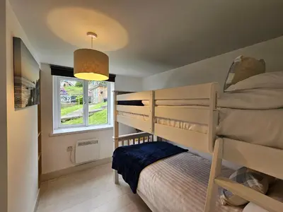 a bedroom with two bunk beds and a window at Luxury Sea View Chalet At Millendreath in Looe