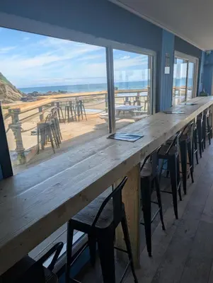 a long wooden table with chairs and a view of the beach at Luxury Sea View Chalet At Millendreath in Looe