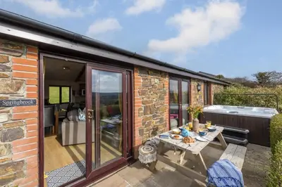 an extension to a stone cottage with a table on a patio at Hot Tub Bungalow - Close to Portreath - Free WiFi - Free Parking - Pet Friendly in Redruth