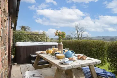a wooden table with food on it on a patio at Hot Tub Bungalow - Close to Portreath - Free WiFi - Free Parking - Pet Friendly in Redruth