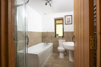 a bathroom with a tub and a toilet and a sink at Hot Tub Bungalow - Close to Portreath - Free WiFi - Free Parking - Pet Friendly in Redruth