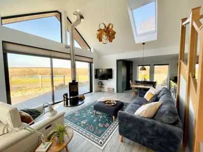 a living room with a couch and a large window at The Lake House , luxury rural retreat in Ladock