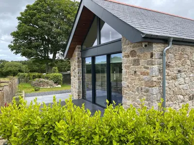 a stone house with black windows and a slate roof at The Lake House , luxury rural retreat in Ladock