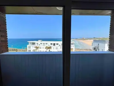 a view of the ocean from a room with two windows at C8 Bay Apartments - Fistral Beach View - Newquay in Newquay