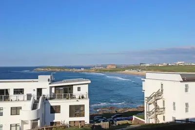 a white building next to a body of water at C8 Bay Apartments - Fistral Beach View - Newquay in Newquay