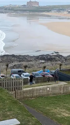 a group of cars parked next to the beach at C8 Bay Apartments - Fistral Beach View - Newquay in Newquay