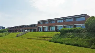 a building with a grassy field in front of a building at C8 Bay Apartments - Fistral Beach View - Newquay in Newquay