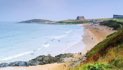 a group of people on a beach with the ocean at C8 Bay Apartments - Fistral Beach View - Newquay in Newquay