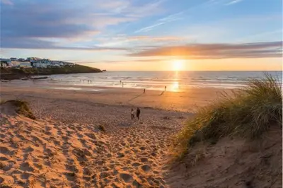 a couple of people walking on a beach at sunset at C8 Bay Apartments - Fistral Beach View - Newquay in Newquay