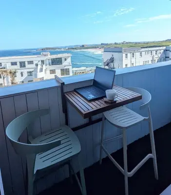 a table and chairs with a laptop on a balcony at C8 Bay Apartments - Fistral Beach View - Newquay in Newquay