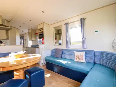 a living room with a blue couch and a table at Little Trevorrick Caravan in Wadebridge