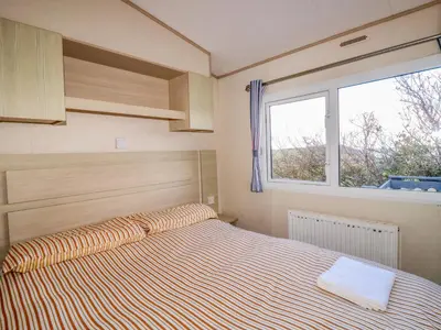 a bedroom with a bed and a window at Little Trevorrick Caravan in Wadebridge
