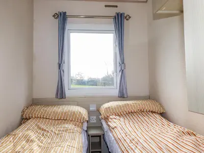 two beds in a room with a window at Little Trevorrick Caravan in Wadebridge