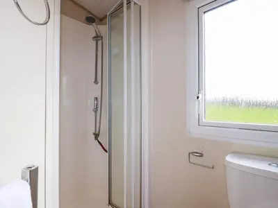 a glass shower in a bathroom with a window at Little Trevorrick Caravan in Wadebridge