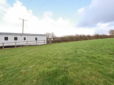 a large field next to a white building at Little Trevorrick Caravan in Wadebridge