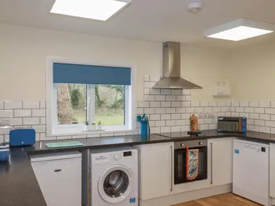 a kitchen with a washing machine and a window at Kingfisher Lodge in St Austell
