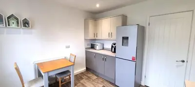 a kitchen with a refrigerator and a table in it at Cornerways, Nr Perranporth in Perranzabuloe