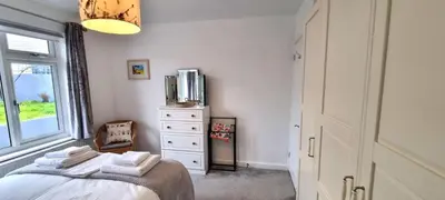 a bedroom with a bed with a dresser and a window at Cornerways, Nr Perranporth in Perranzabuloe