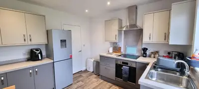 a kitchen with white cabinets and stainless steel appliances at Cornerways, Nr Perranporth in Perranzabuloe