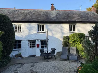 a white house with a table and chairs in front of it at 2 Rose Cottage in St. Agnes