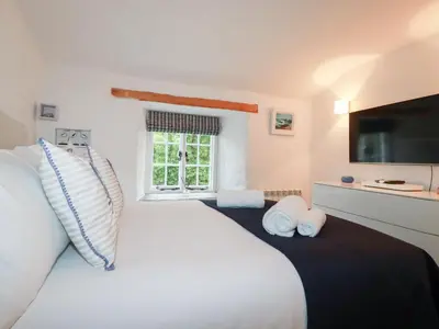 a bedroom with a large white bed and a window at 2 Rose Cottage in St. Agnes