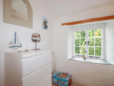 a white room with a window and a dresser at 2 Rose Cottage in St. Agnes