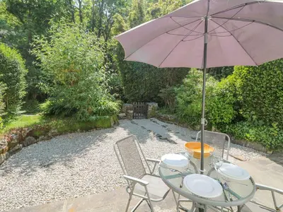 a table with an umbrella and two chairs at 2 Rose Cottage in St. Agnes