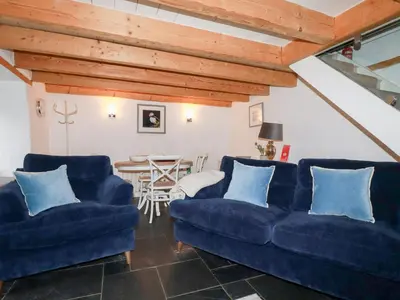 a living room with two blue couches and a table at 2 Rose Cottage in St. Agnes