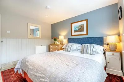 a bedroom with a large bed with a blue headboard at 2 Bed in Little Petherick oc-o30788 in Little Petherick