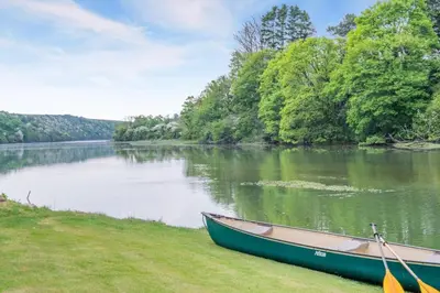 a boat sitting on the grass next to a river at 1 Bed in Little Petherick oc-a30789 in Little Petherick