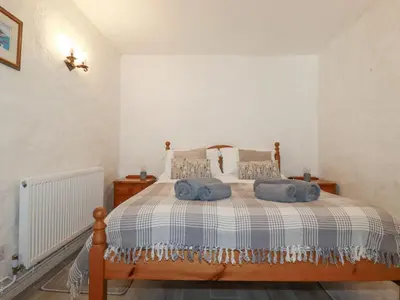 a bedroom with a bed with blue pillows on it at Swallow Cottage in St Austell