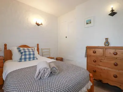 a bedroom with a bed and a wooden dresser at Swallow Cottage in St Austell