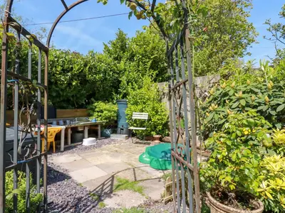 a garden with a gate and a table and chairs at Swallow Cottage in St Austell