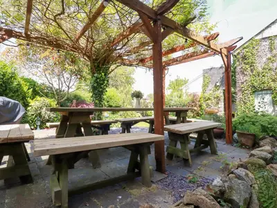 a wooden picnic table under a wooden pergola at Swallow Cottage in St Austell