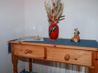 a red vase sitting on top of a wooden dresser at The Hayloft in St Austell