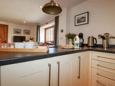 a kitchen with white cabinets and a black counter top at The Hayloft in St Austell