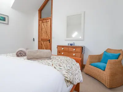 a bedroom with a bed and a chair at The Hayloft in St Austell