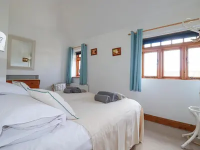 two twin beds in a room with a window at The Hayloft in St Austell
