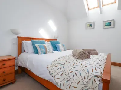 a bedroom with a large bed with blue pillows at The Hayloft in St Austell