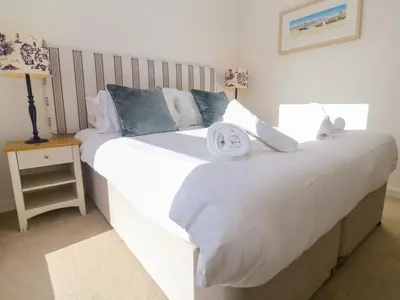 a bedroom with a large white bed and a night stand at Una, Lodge 77 in St Ives