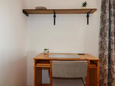 a wooden desk with a laptop and a shelf on a wall at The Old Milking Parlour in Par
