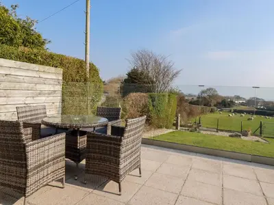 a patio with a table and chairs and a view of a field at The Old Milking Parlour in Par